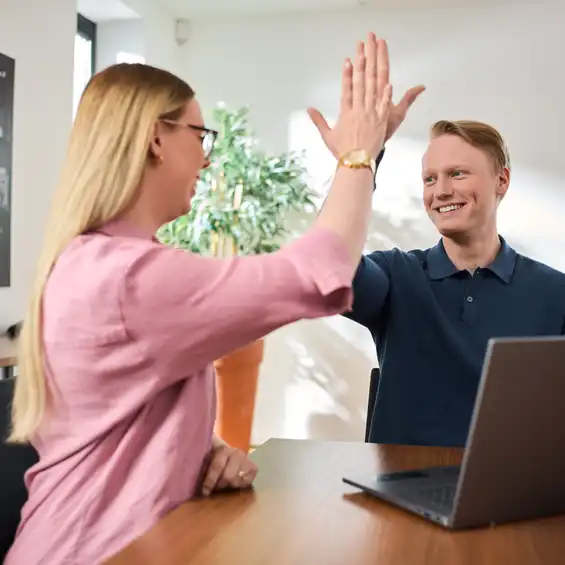 Eine Frau und ein Mann sitzen am Tisch un klatschen sich ab