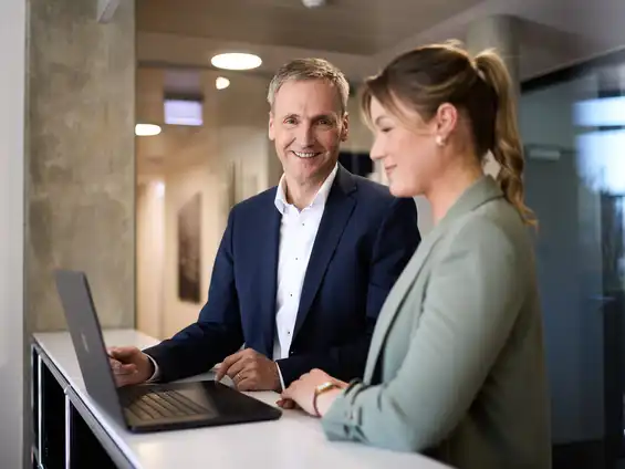 Eine Frau und ein Mann stehen an einem Tisch vor einem Laptop